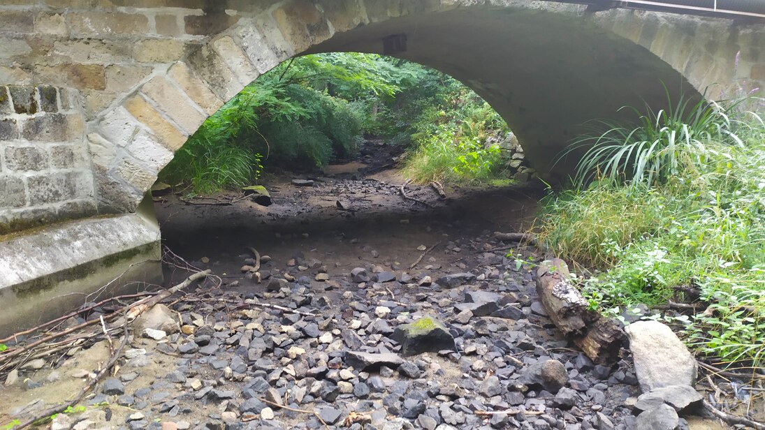 Trocken gefallener Bach unter einer Brücke