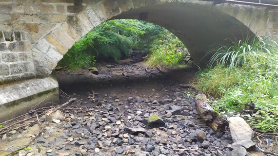 Trocken gefallener Bach unter einer Brücke